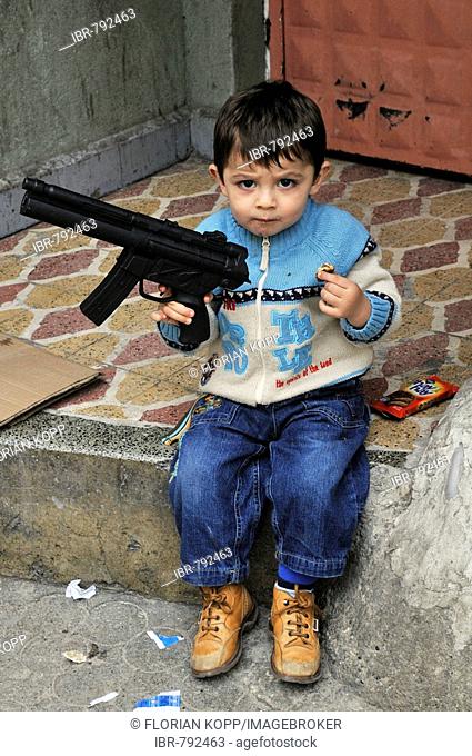 Boy brandishing a toy plastic machine gun, Istanbul, Turkey