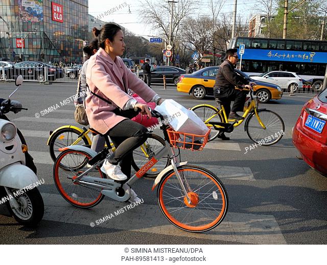 A woman rides a bicycle of the rental bike company 'mobike' on a street in Beijing, China, 28 March 2017. Photo: Simina Mistreanu/dpa | usage worldwide