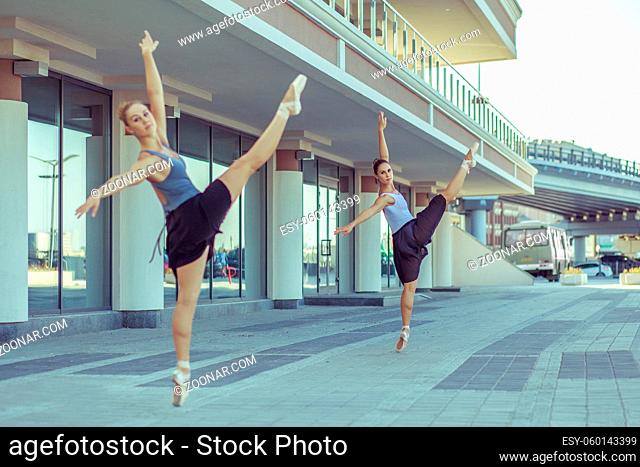 Two young beautiful twin sister dancing ballet in the city with ballet costume. urban sync dance. industrial street dancing. with special effect
