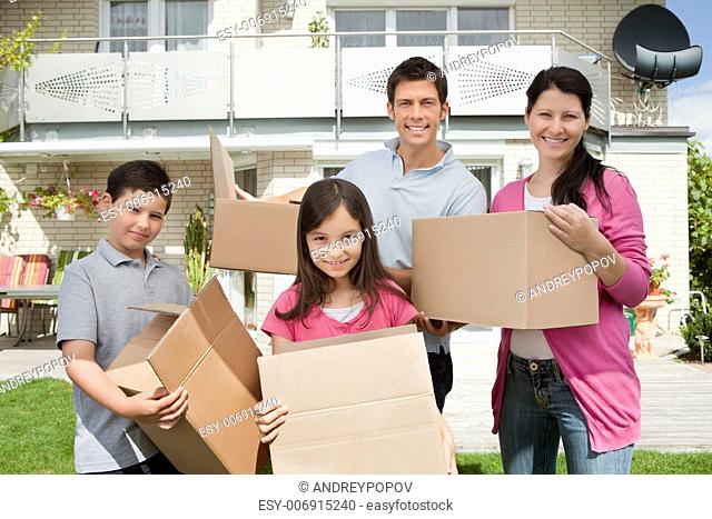 Happy young family moving into new home carrying boxes