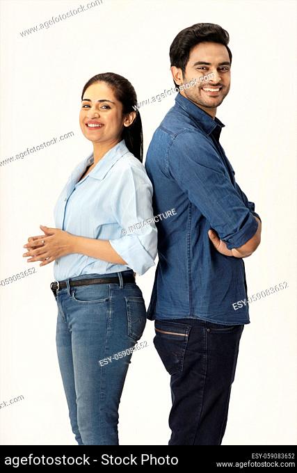 A STYLISH COUPLE HAPPILY STANDING AND POSING IN FRONT OF CAMERA