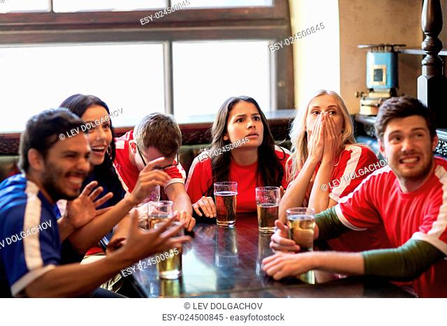 people, leisure, rivalry and sport concept - friends or football fans drinking beer and watching soccer game or match at bar or pub