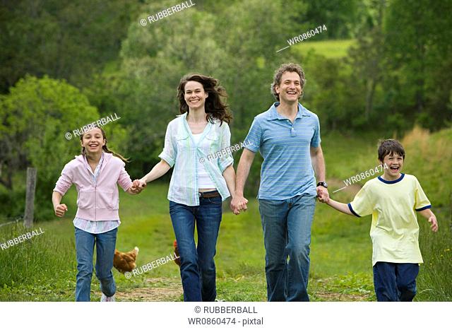 woman and a man with their son and daughter running in a field