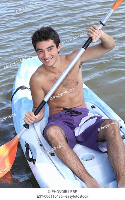 Young man paddling in an open kayak