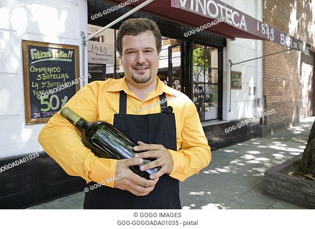 Male employee holding wine bottle outside store
