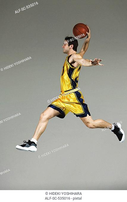 Young man jumping and holding basketball