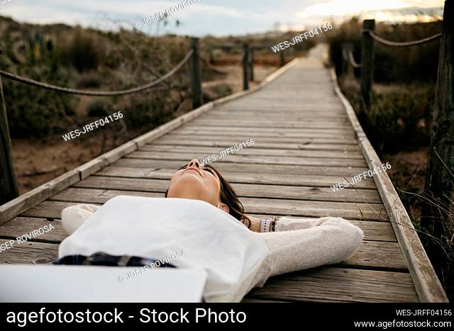Woman lying on a boardwalk in the countryside with laptop