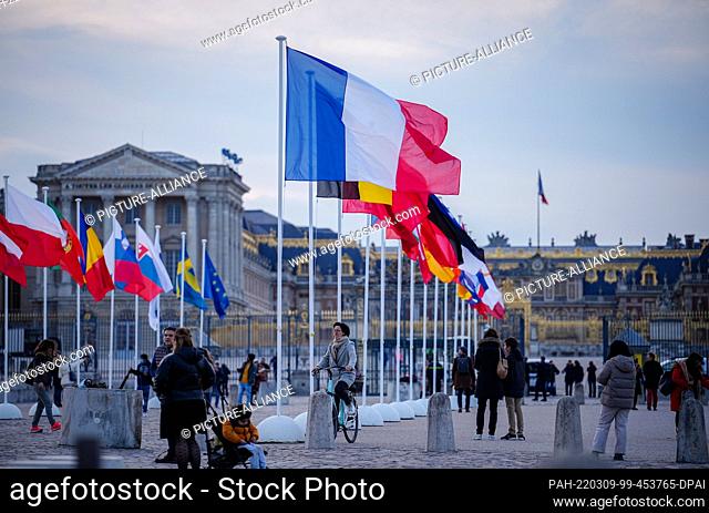 09 March 2022, France, Versailles: The flags of the EU member states are waving in the wind in front of the chateau in Versailles