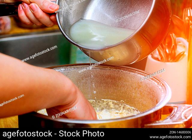 Pouring water into bowl with flour on table in a bakery