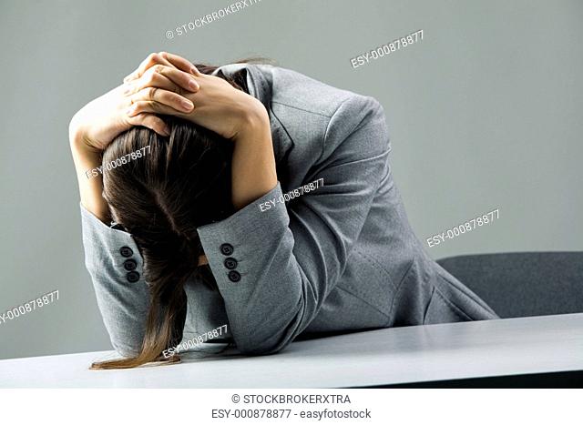 Photo of depressed female sitting at workplace and grieving