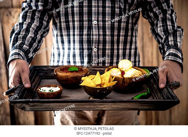 Man with snacks and dips (Mexican food)
