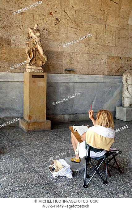 Designer in front of a statue in the Ancient Agora Museum (Stoa of Attalos), Athens. Greece