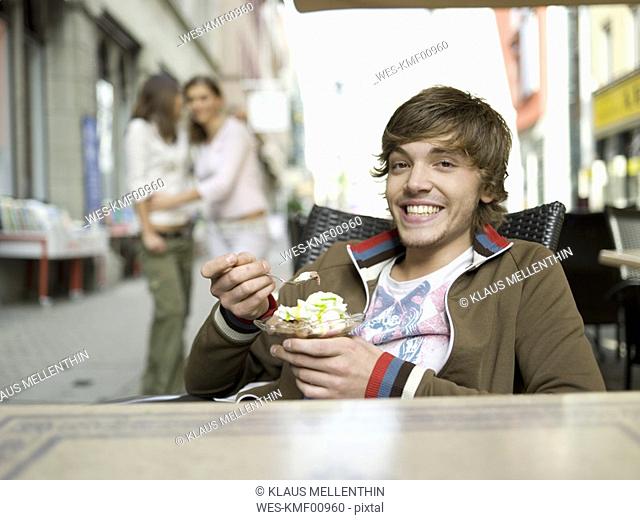 Young man in ice cream parlour, girls watching in background