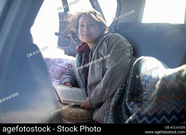 Serene woman reading book at back of car