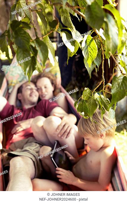 Twig with leaves, family on hammock on background