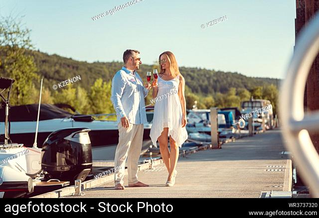 Elegant couple walking between the boats on a river port