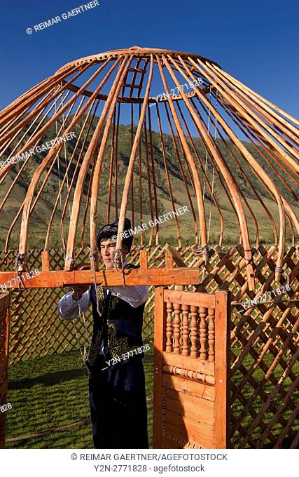 Man in traditional clothes tying the wood frame of a Yurt in Saty Kazakhstan