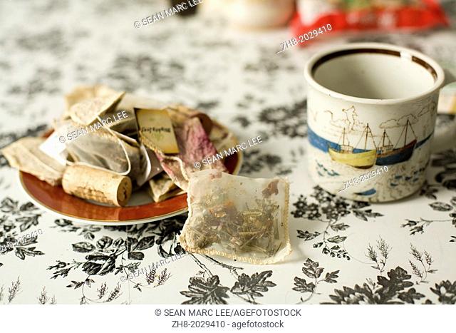 A nautical tea cup next to a dish of teabags, potpourri and an old wine cork