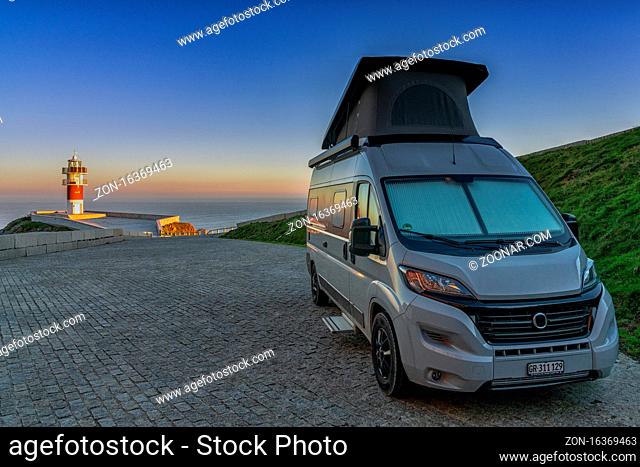 gray camper van parked at Cabo Ortegal lighthouse on the coast of Galicia at sunset