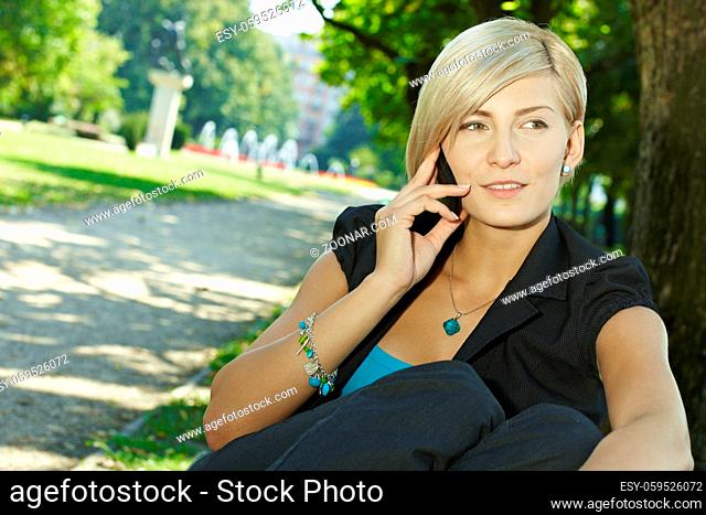 Young businesswoman talking on mobile phone in park, smiling