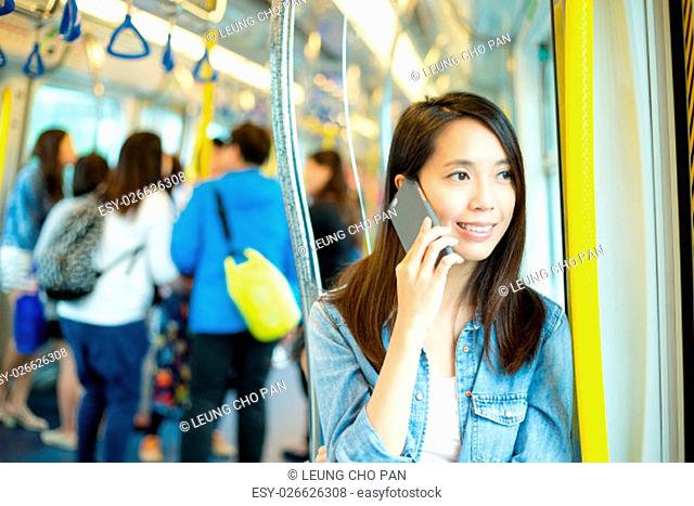 Woman talk to mobile phone in train compartment at hong Kong