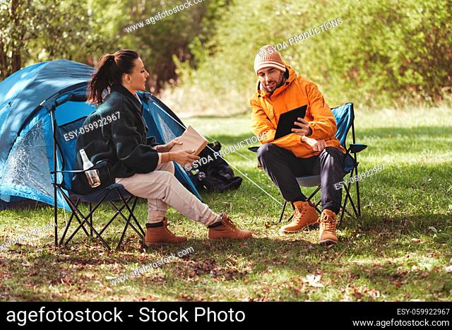 couple with tablet pc and book at tent camp