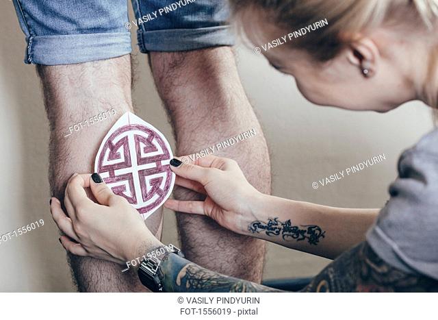 Artist tattoo printing purple design on human leg