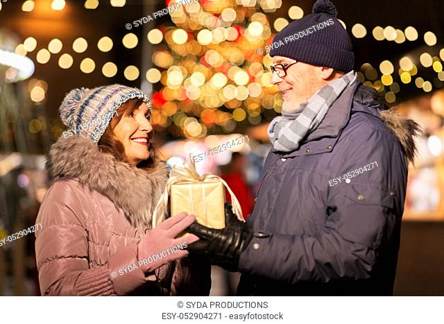 happy senior couple with gift at christmas market