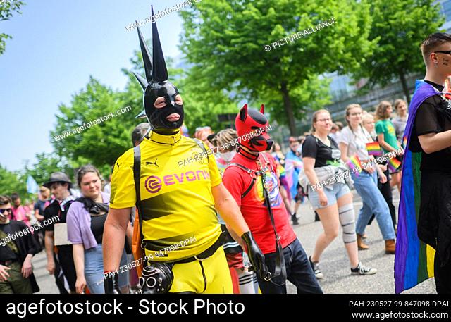 27 May 2023, Lower Saxony, Hanover: A participant in a jersey of Bundesliga team Borussia Dortmund walks through the city center during Christopher Street Day...