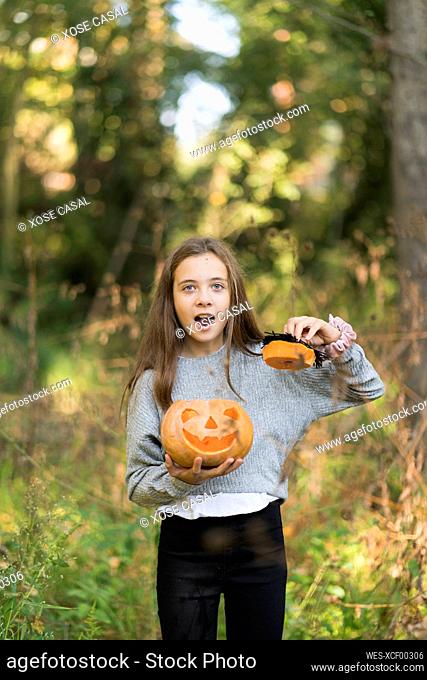 Girl with mouth open standing with Halloween pumpkin at park