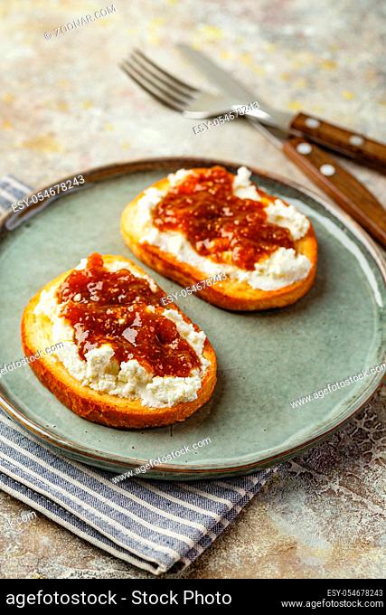 Canape or crostini with toasted baguette, cottage cheese, fig jam on plate. Delicious appetizer, ideal aperitif