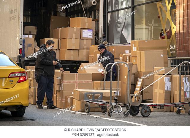 FedEx deliverymen sort a mountain of packages in Soho in New York on Saturday, December 8, 2018 during the Christmas shopping season. (© Richard B