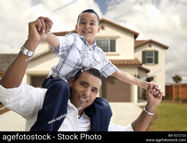 Playful hispanic father and son in front of beautiful house
