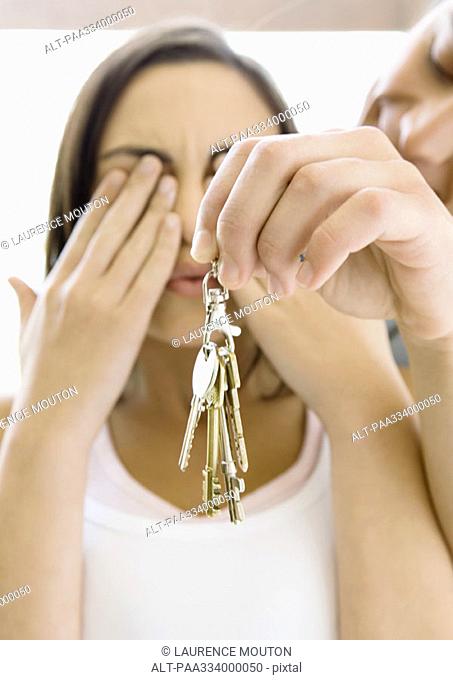 Man holds up keys while woman covers eyes
