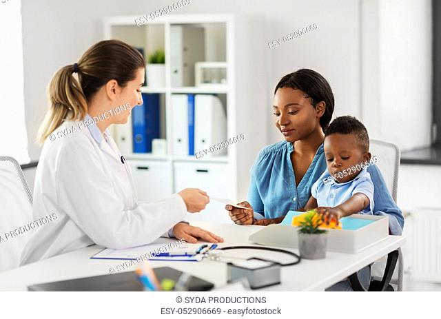 happy mother with baby son and doctor at clinic