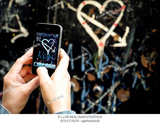 Heart with arrow painted on a wall and close-up of female hands with a phone making a photo in the Medina of Fez, Morocco, Africa