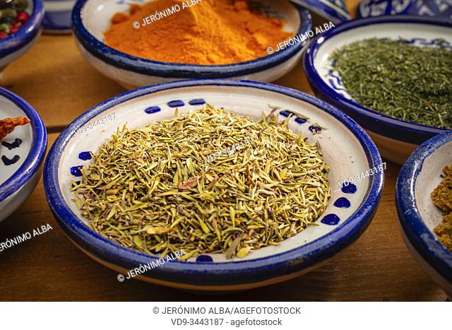 Healthy food. Spices in ceramic containers typical of Morocco on an old wooden table. Colored pepper, curcuma, cayenne, cumin, dill and thyme