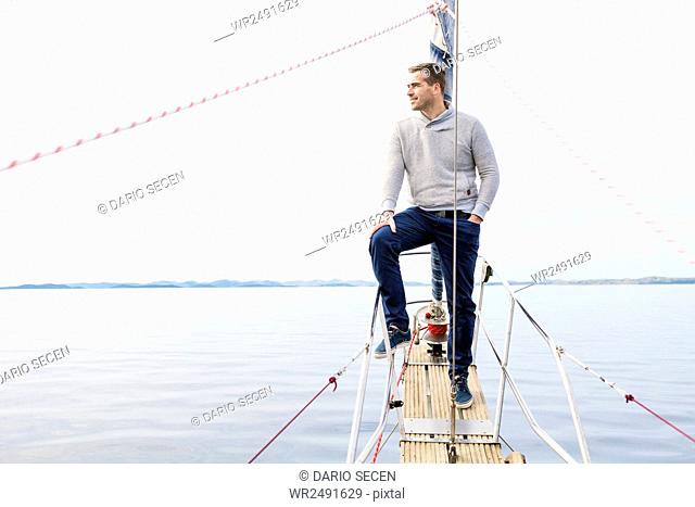 Man stands on bow of yacht day looking at sea