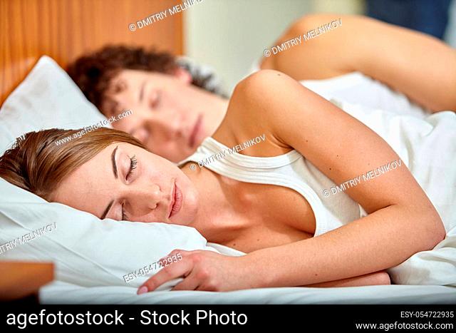 Happy young family sleep in the bed at home. Selective focus on woman