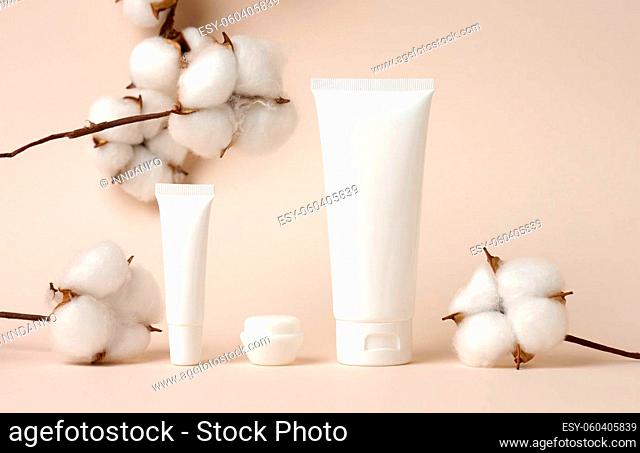 jar and empty white plastic tubes for cosmetics on a green background. Packaging for cream, gel, serum, advertising and product promotion, mock up