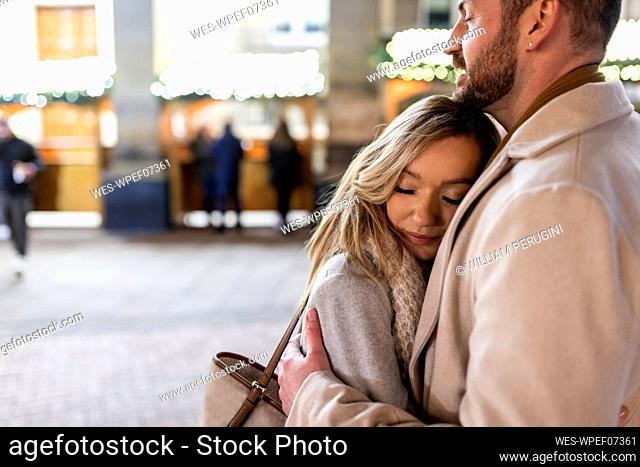 Young woman hugging man at Christmas market