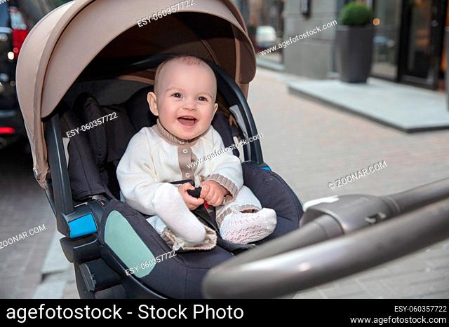 Smile little baby sitting in a stroller outdoors