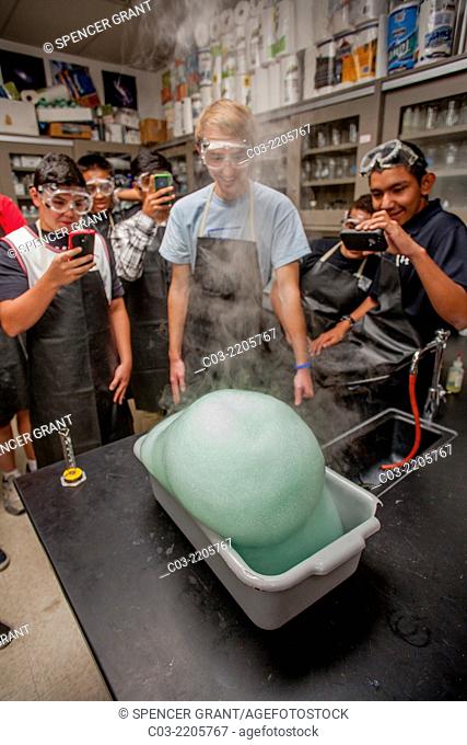 San Clemente, CA, high school chemistry students watch as hydrogen peroxide, soap, and sodium iodide are mixed to produce an expanding foam of oxygen trapped in...