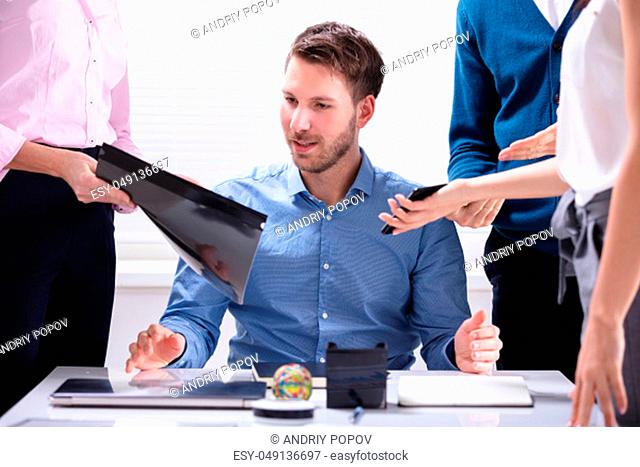 Young Businessman Looking At Document Shown By Partner