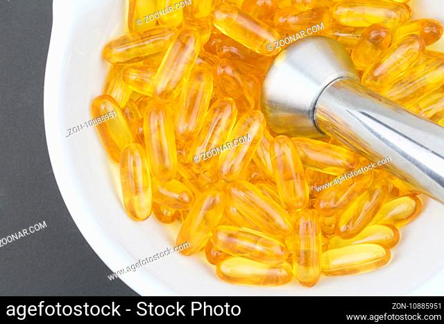 Fish oil with Omega 3 closeup in mortar and pestle on black background