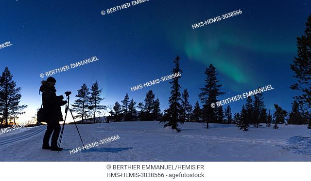 Finland, Lapland, Muonio, photographer under northern light above Pallas-Yllästunturi nationalpark