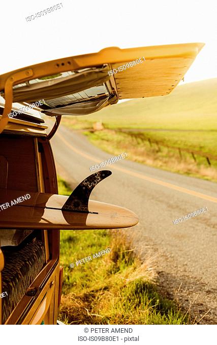 Yellow surfboard in vintage recreational vehicle boot on roadside, Exeter, California, USA