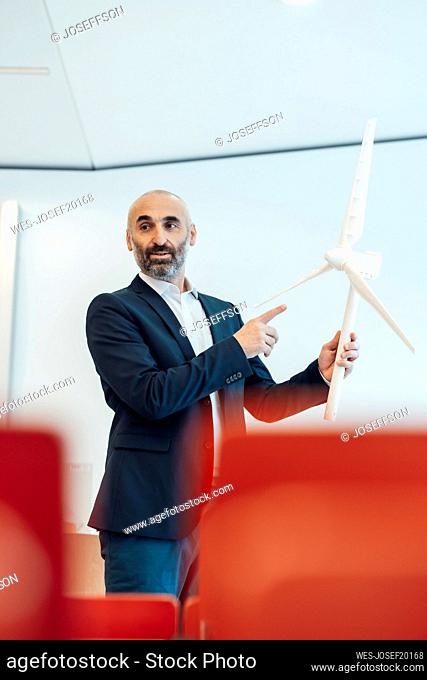 Mature businessman explaining and having meeting over wind turbine