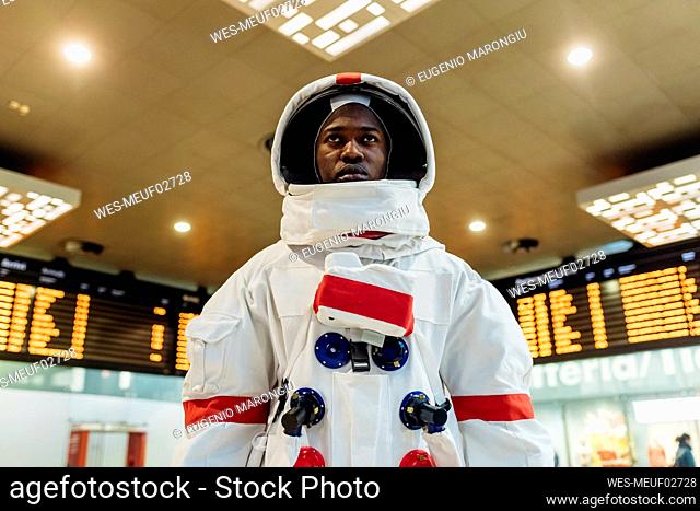 Male astronaut wearing space suit standing at arrival departure board