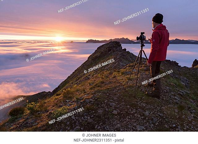 Man photographing mountains at sunrise